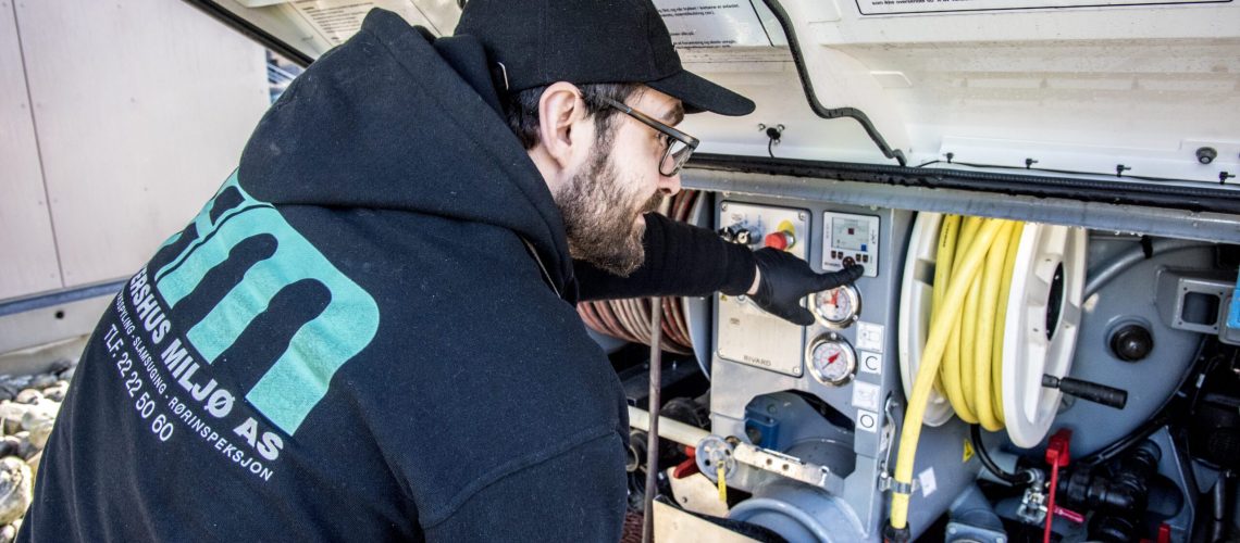 bildet viser ansatt i Akershus Miljø AS inne i en firmabil på oppdrag.